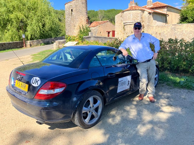 Customer who took part in a classic car rally standing next to his Mercedes in France